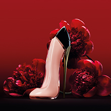 Parfümflakon in Form eines rosafarbenen High Heels mit schwarzer Spitze und goldenem Absatz, vor einem roten Hintergrund mit Rosenblüten. Beschriftung darunter: 'Good Girl Blush'.