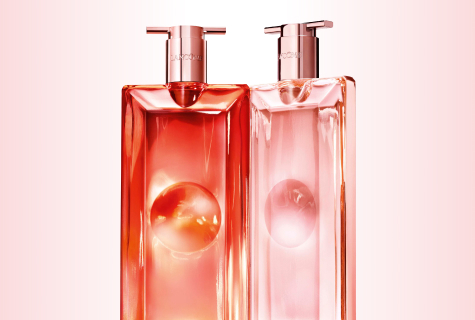 Lancôme Idôle Duftflakons in korall- und rosafarbenem Design mit Pumpaufsatz vor hellem Hintergrund.